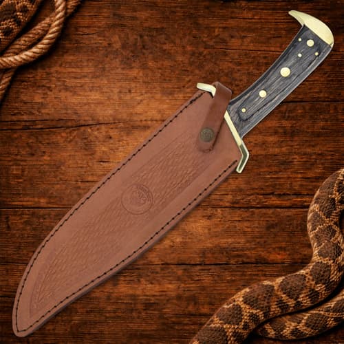 Knife in leather sheath on wooden background with coiled rope