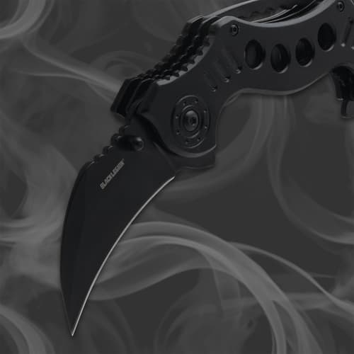 Close-up of a black folding knife blade with smoky background