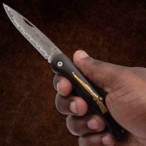 Hand holding a folding knife with patterned blade