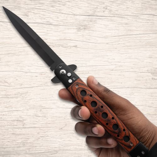 Hand holding a stiletto knife with wooden handle