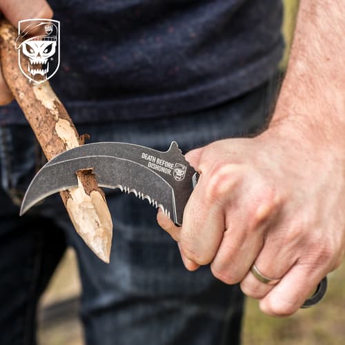 Person carving wood with a curved knife outdoors