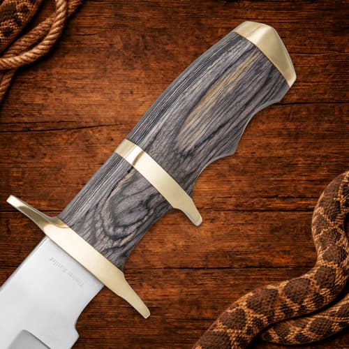 Close-up of knife handle with wood grain and brass accents