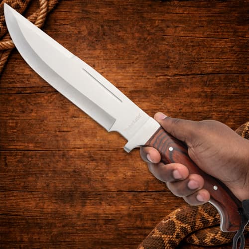 Hand holding a large knife with wooden handle