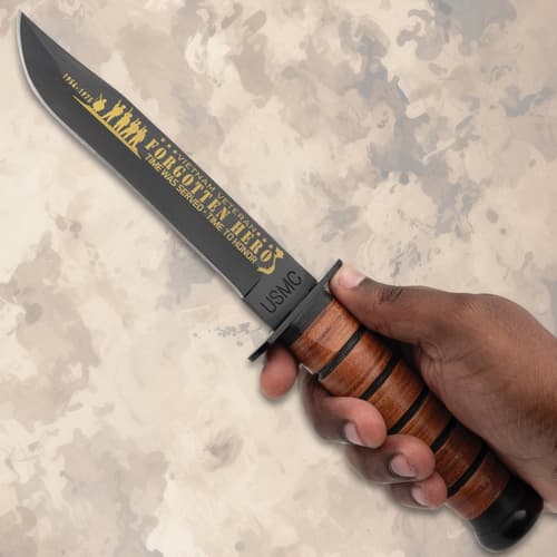Hand holding a commemorative knife with leather handle