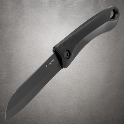 Open black ceramic pocket knife at an angle, showing the blade edge and curved handle with a pommel hole