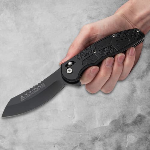 Hand holding a black folding knife with textured handle