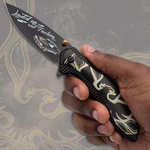 Hand holding a black pocket knife with decorative handle