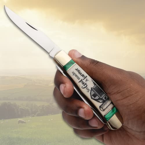 Hand holding a pocket knife with farm-themed handle