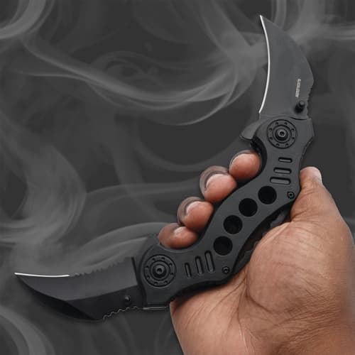 Hand holding a black folding knife with dual blades