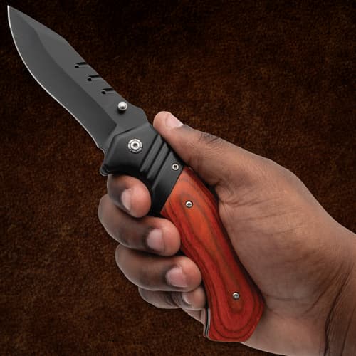 Hand holding a folding knife with wooden handle