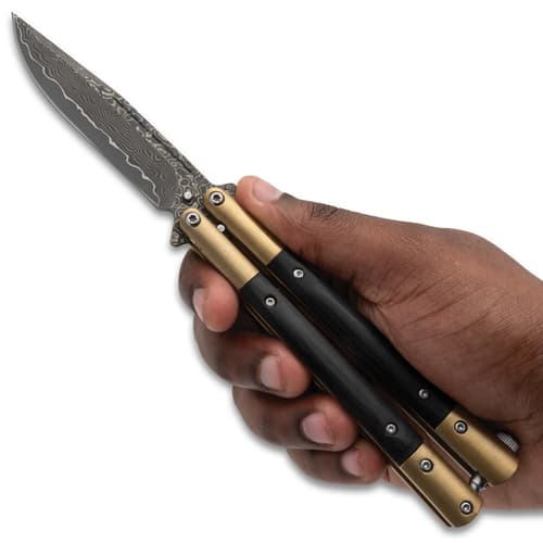 Hand holding a butterfly knife with a patterned blade