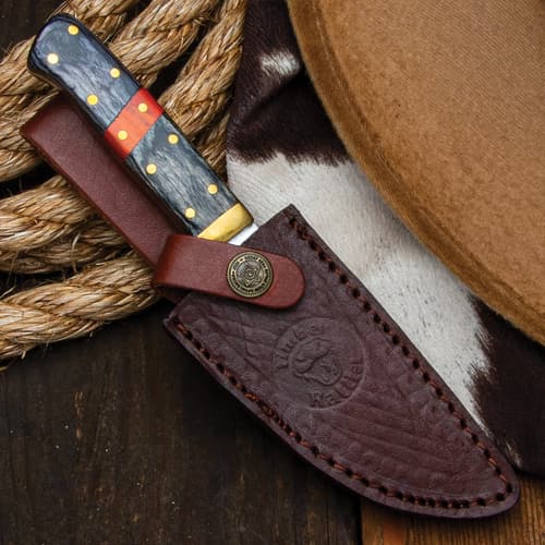 Knife in leather sheath on a cowboy hat and rope background
