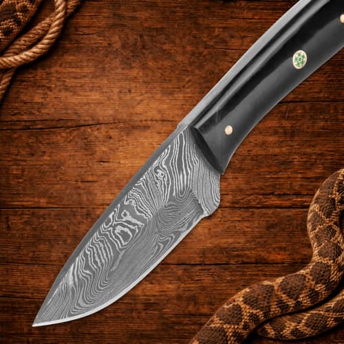 Knife blade with Damascus pattern on wooden surface