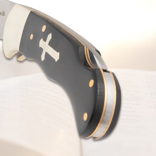 Close-up of knife handle with cross inlay on open book