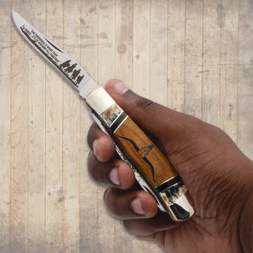 Hand holding a knife with engraved blade and wooden handle