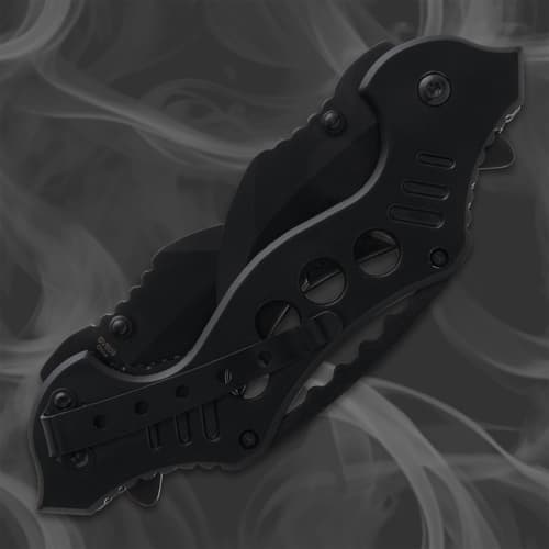 Closed black folding knife with pocket clip on smoky background