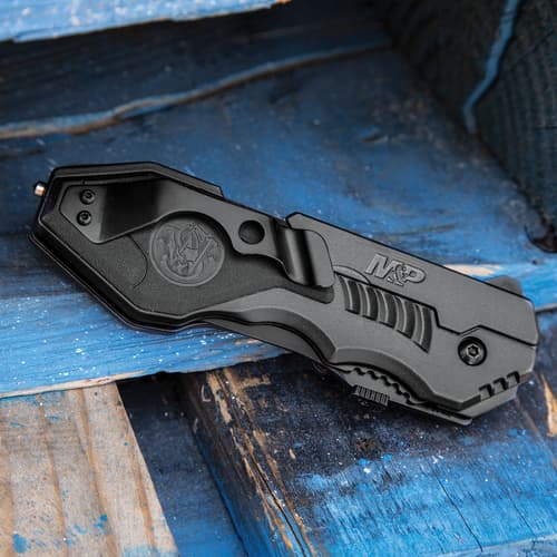 Closed tactical knife with clip on blue wooden surface