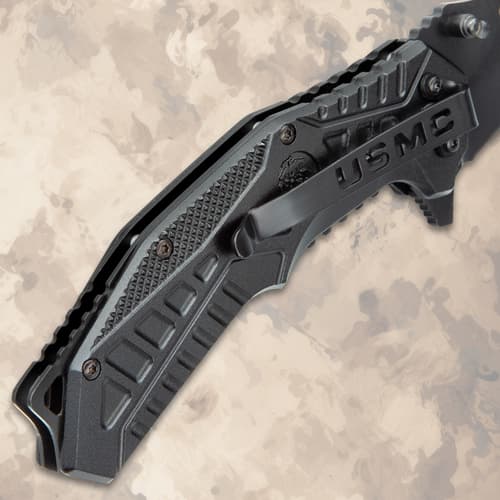 Close-up of closed black tactical knife with USMC clip