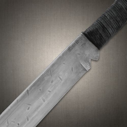 Close-up of machete blade near handle with engravings