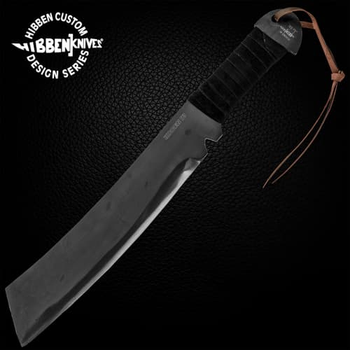 Gil HIbben IV Machete Knife is one solid piece of 1090 carbon steel and has a black cord wrapped handle, shown on wooden background.