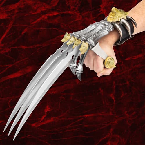 Hand holding a claw weapon with wolf and lion motifs