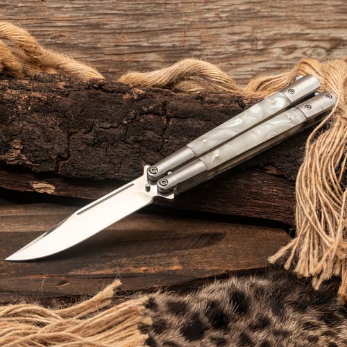 Butterfly knife with pearl handles on rustic wood and rope