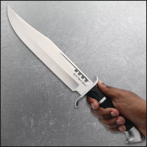 Hand holding a large knife with a black handle