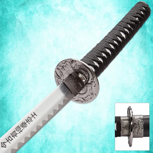 Close-up of katana handle and engraved guard on blue background