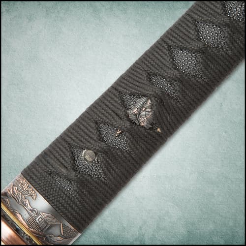 Under the ray skin and black cord wrapped handle is a antiqued cast collar depicting a house and scenery.