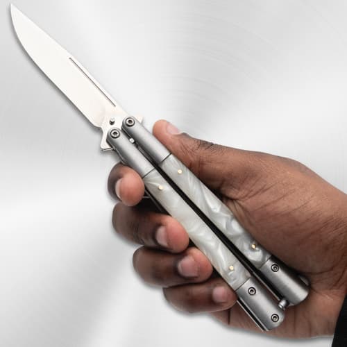 Hand holding a butterfly knife with pearl handles