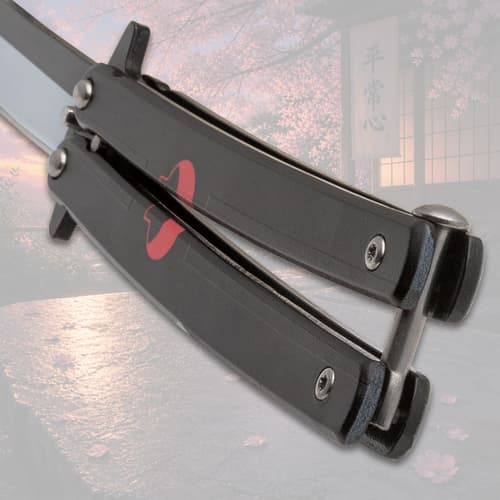 Close-up of black butterfly knife handle with red design