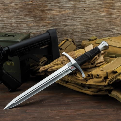 Dagger placed on tactical gear with a wooden background