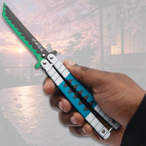 Hand holding open butterfly knife with blue and green design