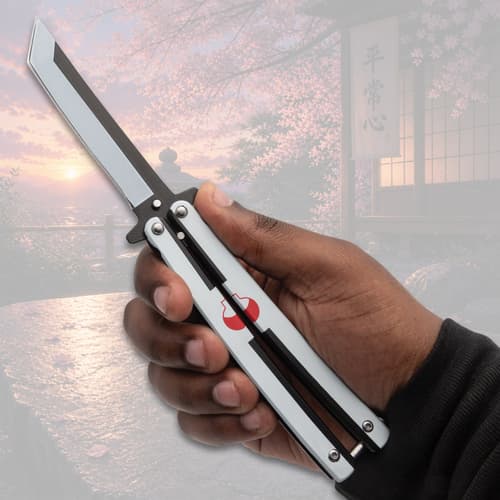Hand holding a butterfly knife with scenic background