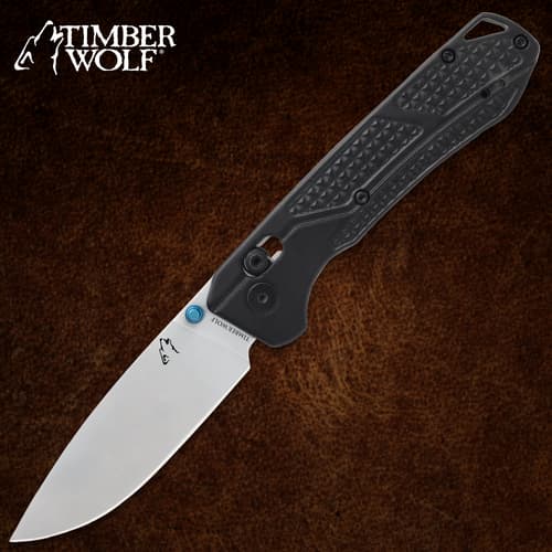 Black folding knife with textured handle on brown background