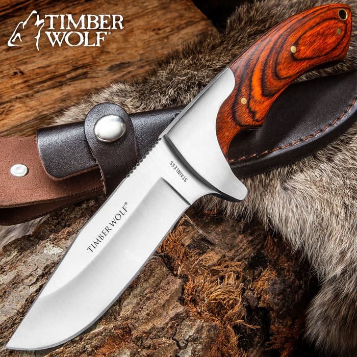 Timber Wold Blazin’ Fixed Blade Knife with stainless steel blade and hardwood handle shown next to sheath on a background of furs.