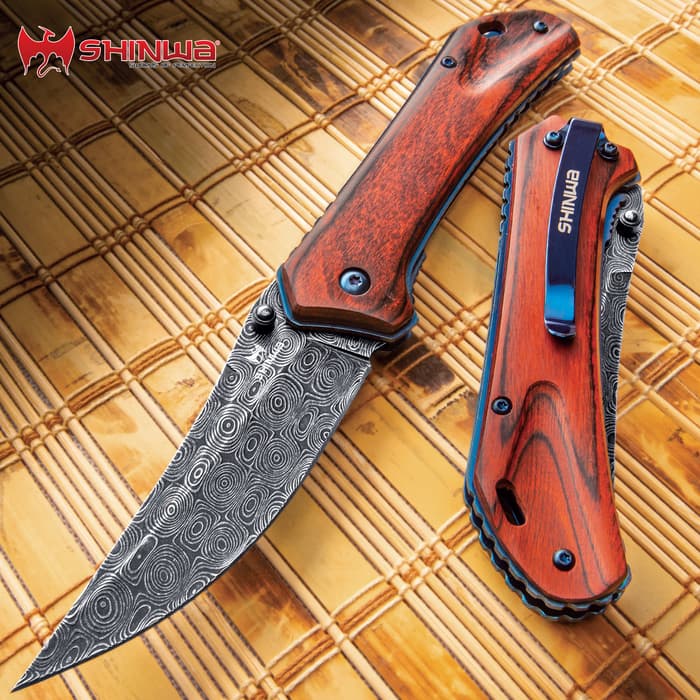 Shinwa Zhanshi Bloodwood Pocket Knife has a reddish-brown handle with dark grey stainless steel blade, shown on bamboo background.