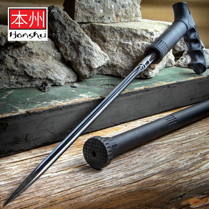 Honshu Sword Cane shown with blade outside of the cane housing on a wooden surface next to rocks. 