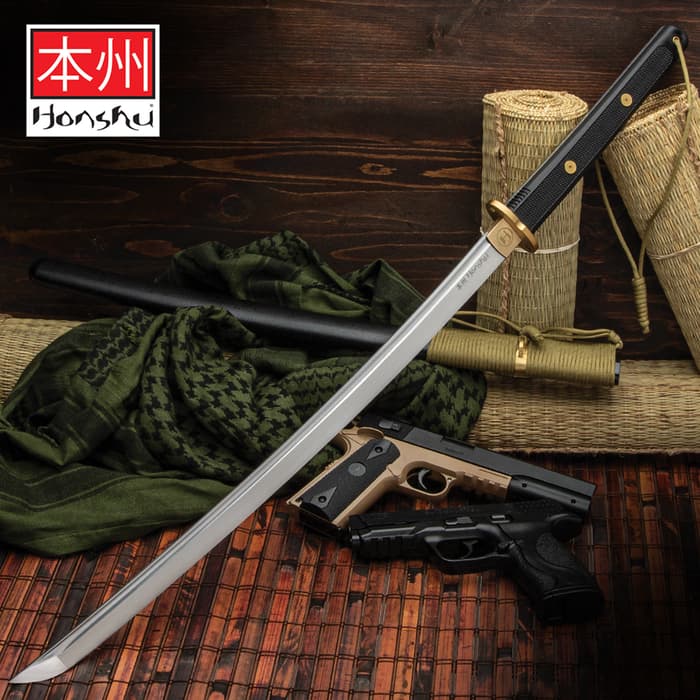 Honshu wakizashi sword with black and brass handle shown in front of other weapons on tatami mats. 