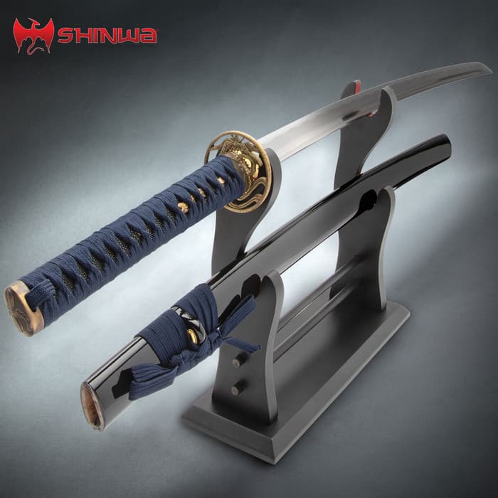 Shinwa Dragonfly Katana shown on black wooden stand with blue cord wrapped handle and black sheath. 