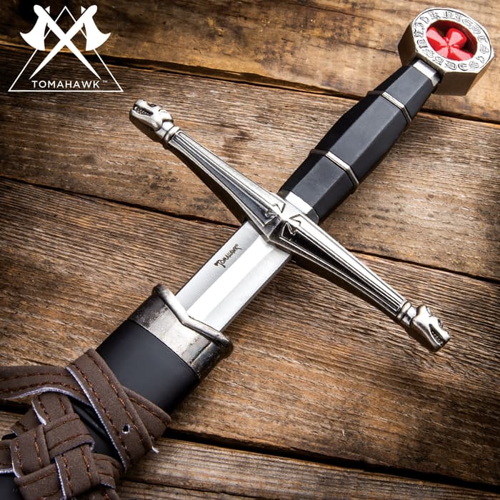Tomahawk medieval sword shown with ornate cross guard, black handle, and red cross inside the pommel. 
