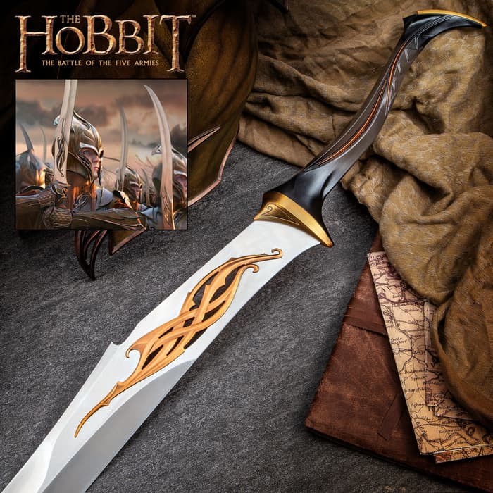 The Hobbit Mirkwood Infantry Sword shown with bronze-finished metal hilt atop brown cloths and a map next to a movie still. 