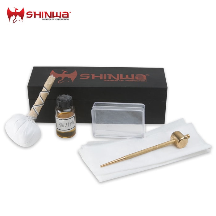 Shinwa sword cleaning kit shown with black wooden box, brass awl, rice papers, uchiko powder ball, and bottle of oil. 
