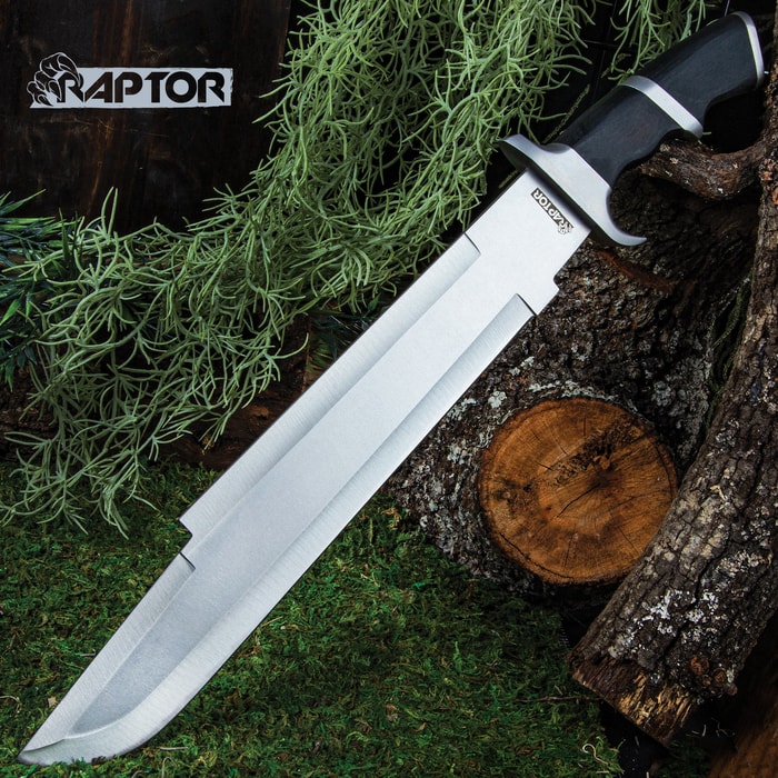 Raptor Machete shown on an outdoor background with massive stainless steel blade and black pakkawood handle.