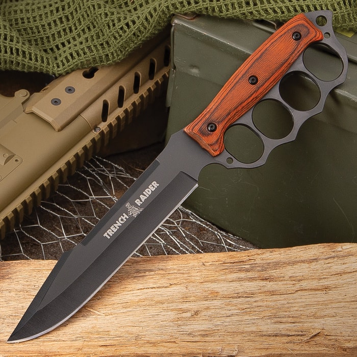 "Trench Raider" matte black trench raider knife with pakkawood handle scales and knuckle buster handle on a background of military gear.

