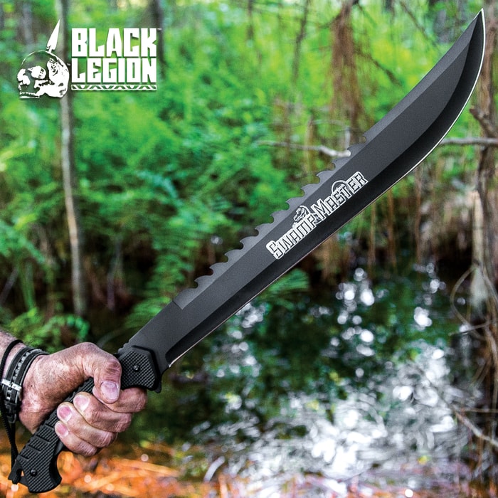 The Black Legion Swamp Master Machete Knife is shown held in front of a swamp background with 18” black stainless steel blade with “gator tooth” spine.