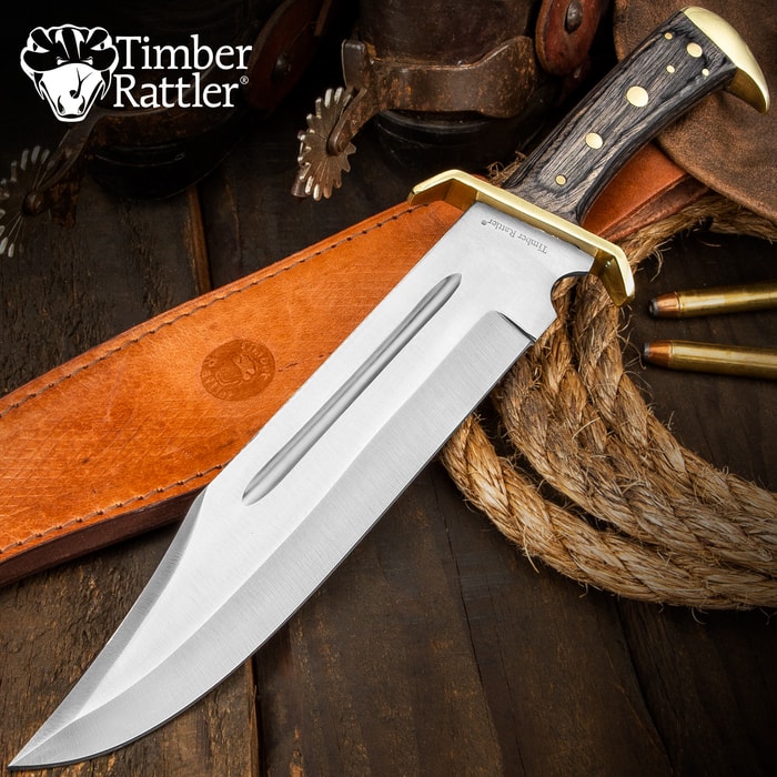 Timber Rattler Western Outlaw Bowie Knife has a stainless steel blade and gray hardwood handle, shown with leather sheath on wooden background.