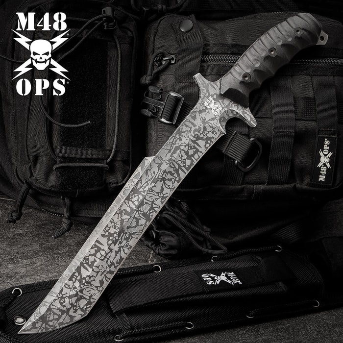 17 3/4" titanium electroplated finish blade M48 combat machete with black TPU handle on a background of black utility gear.
