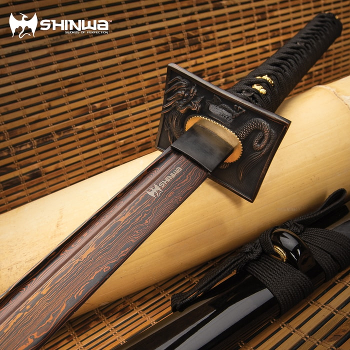 Shinwa Black Knight Katana on bamboo mat, showcasing black Damascus steel blade and ornate dragon tsuba. 