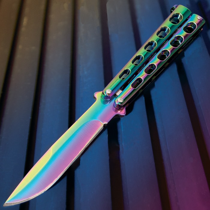 The Rainbow Slotted Butterfly Knife has a 4” stainless steel blade and skeletonized steel handle, both with rainbow finish.